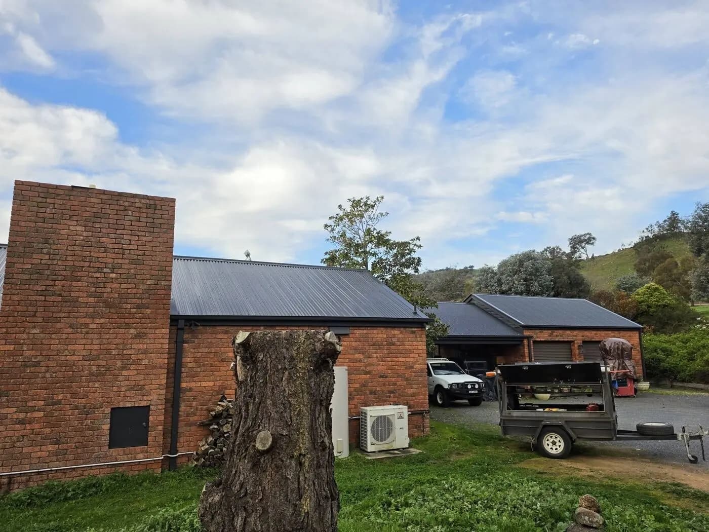 The side of the house and the garage, with the hills behind