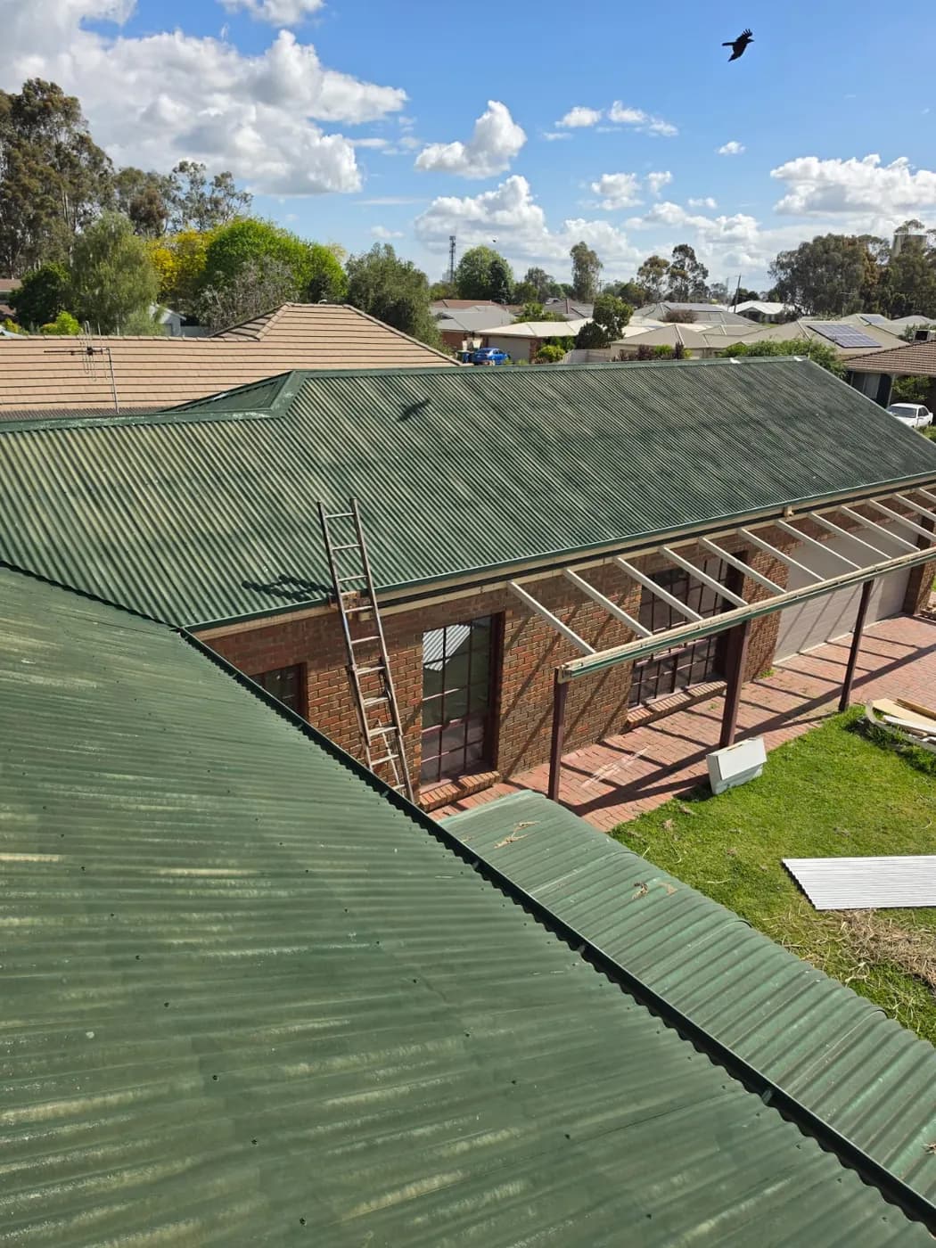 The same roof from the same spot before, the old green paint chalky and streaky