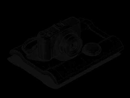 A compact camera resting on a roof tile with its lens cap beside it