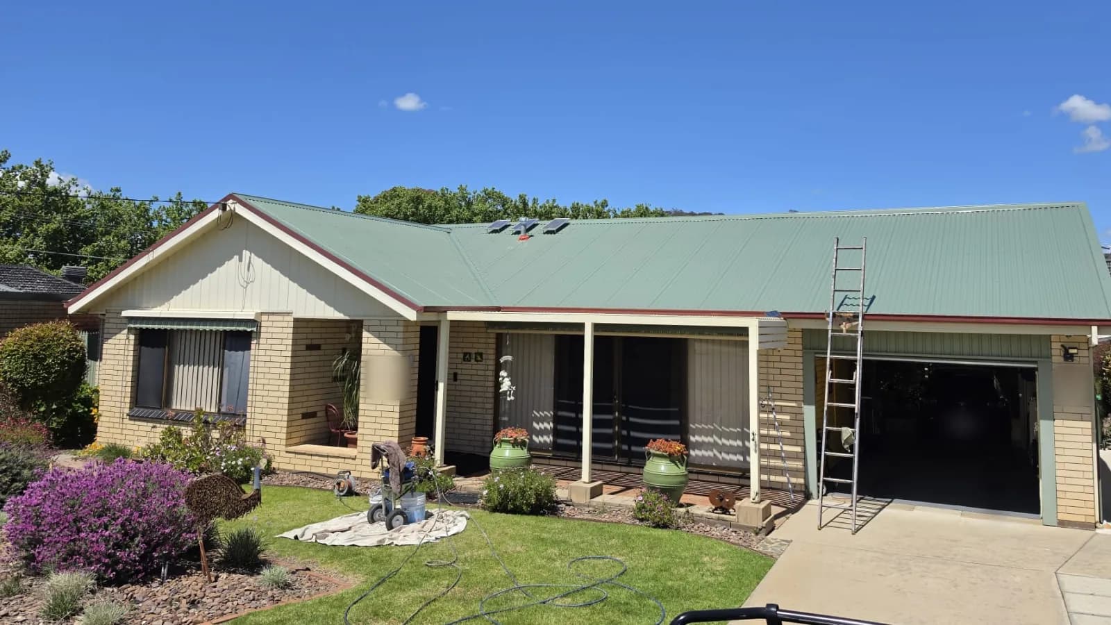 The same home from the same spot, its roof painted in Colorbond Wilderness, after