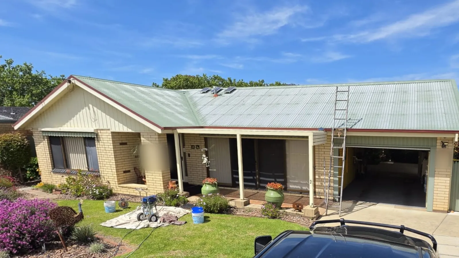 Cream brick home in Wodonga with a faded, worn green corrugated roof and a ladder up, before